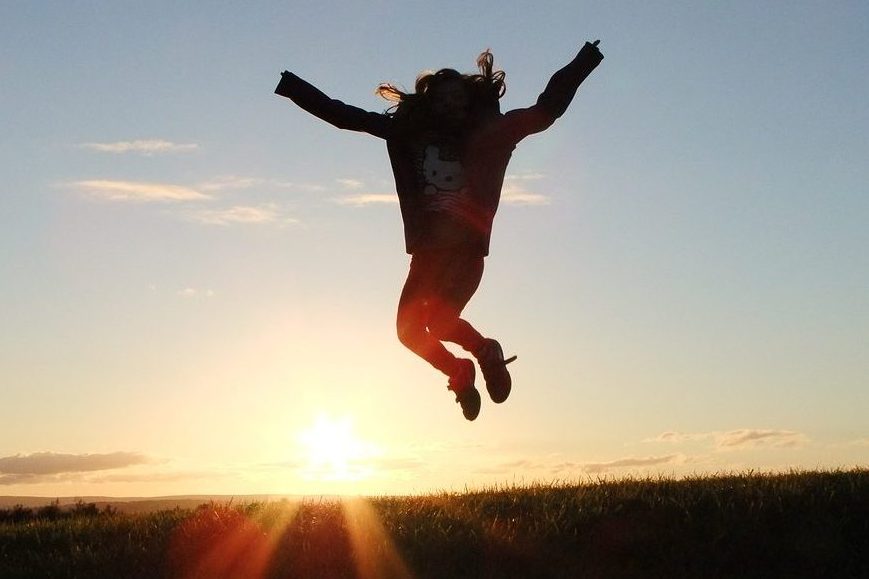 A person jumping for joy with the sun shinning brightly behind them because they are happy to be progressing their career.